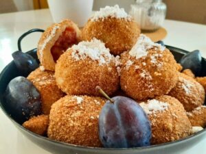 szilvás gombóc recept - egy nagy tálon sok házi szilvásgombóc porcukorral megszórva